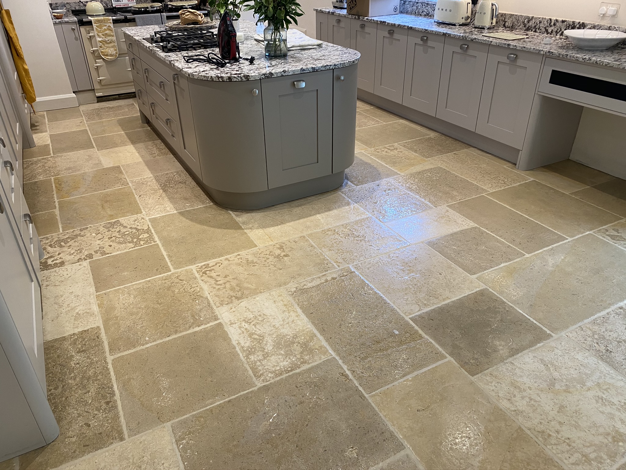 Expertly cleaned and sealed limestone floor tiles and grout line in a kitchen by Proclene